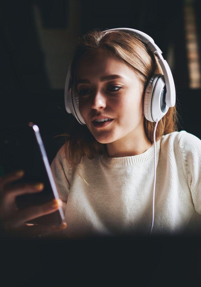 Positive woman listening to music and using phone